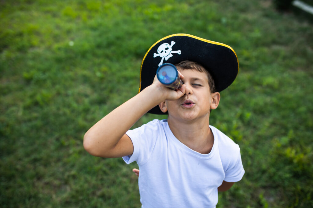 A cute boy is playing make-believe pretending to be a pirate in his yard