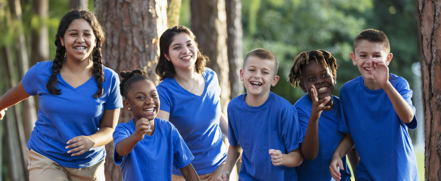 Children in matching blue shirts having fun outside laughing